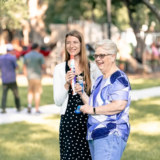 Two women standing in a park eating ice cream